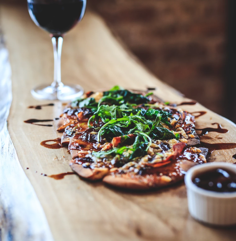 flatbread, with carnalized onoin and balsamic drizzle.  glass of red wine in the background
